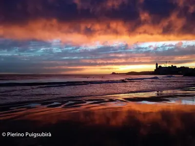 a sunset on a beach with the ocean at Stunning sea views over marina with swimming pool in Sitges