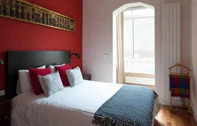 a bedroom with a white bed with red walls and a window at Barcelona - Provença in Barcelona