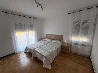 a white bedroom with a bed and two windows at casa en Palau in Palau-Solità i Plegamans