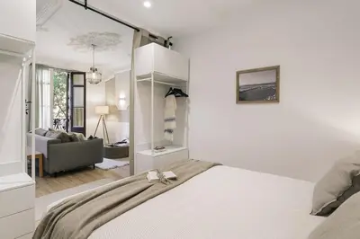a kitchen with white cabinets and a table with chairs at Baia - Studio and balcony in Eixample Esquerra in Barcelona