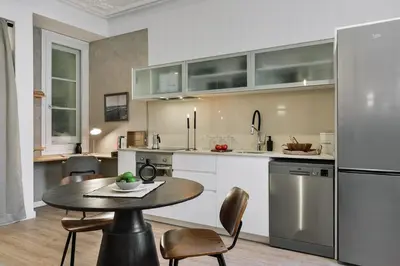 a white bedroom with a bed and a living room at Baia - Studio and balcony in Eixample Esquerra in Barcelona