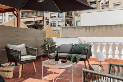 a patio with a couch and chairs and an umbrella at Sishane - 3 bedrooms and terrace in Eixample Esquerra in Barcelona