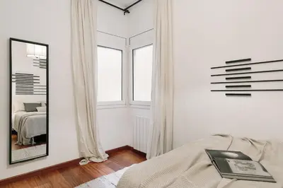 a white bedroom with a bed and a mirror at Tramonto - 3 bedrooms and balcony in Sant Antoni in Barcelona
