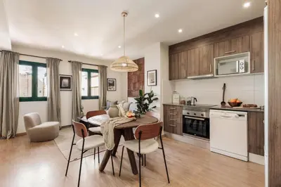 a kitchen with wooden cabinets and a table in a room at Isora - 1 bedroom in El Gòtic in Barcelona