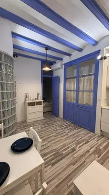 a room with a blue door and a table and chairs at Cosy apartment next to the sea in Barcelona