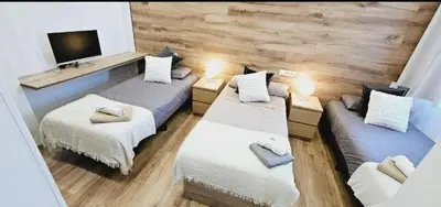 a room with two beds and a flat screen tv at 2 apartamentos juntos ideal grupos cerca Barcelona in Badalona