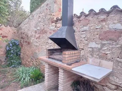 an outdoor stove is sitting on a brick wall at Casa rural Cal Farriol in Mediona