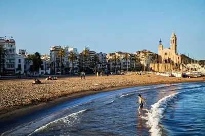 a person walking in the water on a beach at Benet Sitges in Sitges