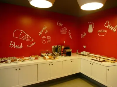 a restaurant with a red wall with drawings on the wall at Hotel Turin Barcelona in Barcelona