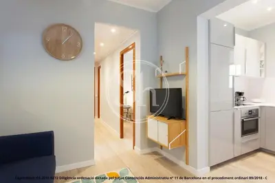 a living room with a tv and a clock on a wall at Bonito apartamento para 3 en Poble Sec in Barcelona