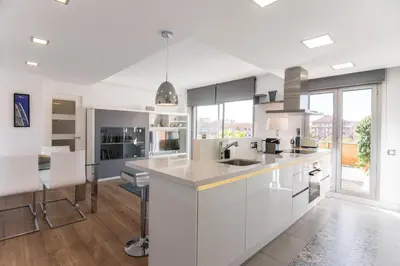 a kitchen with white cabinets and a large window at Glorious Sunny penthouse near the beach in Barcelona