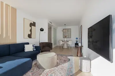 a living room with a blue couch and a tv at Quiet modern 2 bed apartment with Balcony, Pool and Free Parking in Barcelona