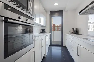 a kitchen with white cabinets and a stove top oven at Quiet modern 2 bed apartment with Balcony, Pool and Free Parking in Barcelona