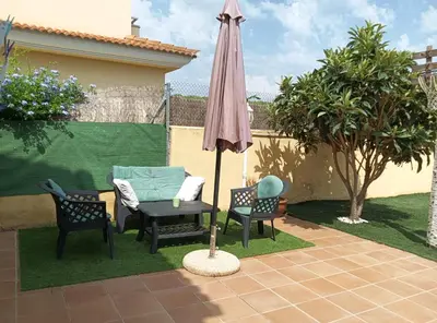 a patio with a table and an umbrella and chairs at Brad House in Can Trabal