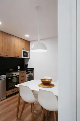 a kitchen with a white table and white chairs at Apartaments Casa Padró in Manresa