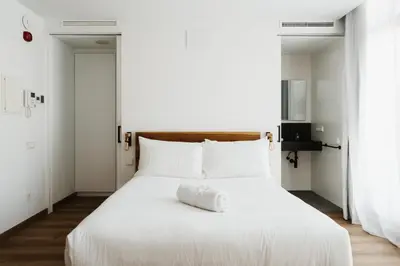 a white bed with white sheets and pillows at Apartaments Casa Padró in Manresa