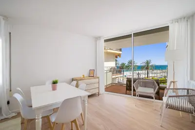 a living room with a table and chairs and a view of the ocean at Sunset Beachfront in Sitges in Sitges