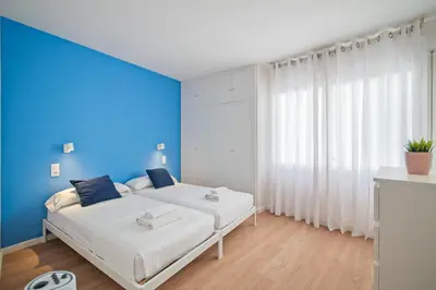a bedroom with two beds and a blue wall at Sunset Beachfront in Sitges in Sitges