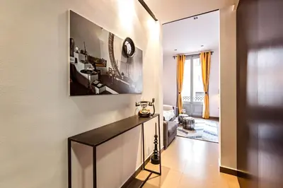 a living room with a table and a clock on the wall at Sweett - Urqui City Center in Barcelona