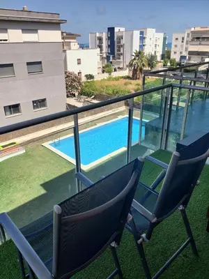 two chairs on a balcony with a swimming pool at Vilanova Beach Stay in Vilanova i la Geltrú