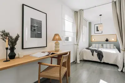 a kitchen with white cabinets and a wooden cutting board at Soffio - Studio and terrace in Gràcia in Barcelona