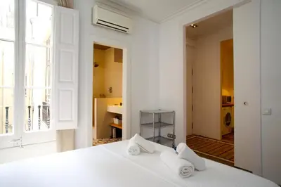 a white bedroom with a bed with towels on it at BarcelonaForRent The Claris Suites II in Barcelona