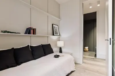 a white bedroom with a bed with a lamp and books at Fiore - 2 bedrooms in Ciutat Vella in Barcelona