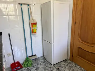 a kitchen with a white refrigerator and mop at Can Bosquet - Casa de invitados adosada a casa familiar in Corbera de Llobregat