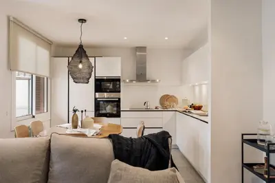 a white kitchen with a wooden table and chairs at Levent - 3 bedrooms and terrace in Sant Antoni in Barcelona