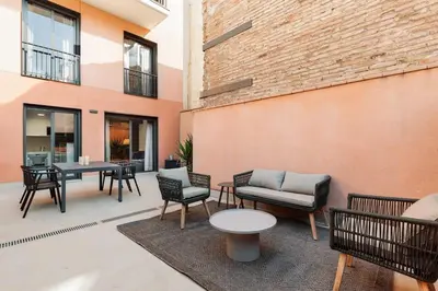 a patio with chairs and tables and a brick wall at Tortosa - 3 bedrooms and a terrace in Les Corts in Barcelona