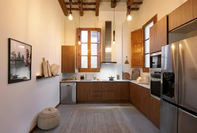 a kitchen with wooden cabinets and a stainless steel refrigerator at Mahoro - 3 bedrooms in Ciutat Vella in Barcelona