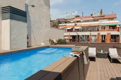 a table and chairs on a balcony with buildings at Lys - 2 bedrooms and pool in Eixample Esquerra in Barcelona