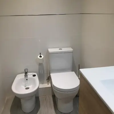 a white bathroom with a toilet and a sink at Apartamento CAMP NOU in Hospitalet de Llobregat