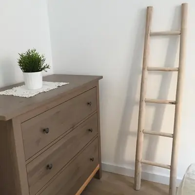 a wooden ladder next to a dresser with a plant on it at Apartamento CAMP NOU in Hospitalet de Llobregat