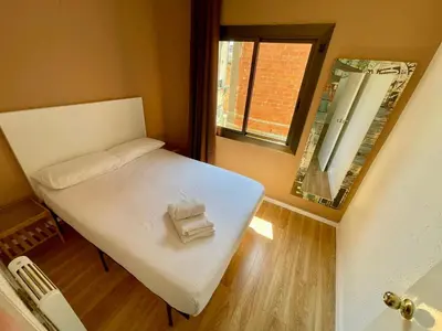 a small bed in a small room with a window at Gran apartamento nuevo de 3 Hab, a 1 minuto del metro HBB in Hospitalet de Llobregat