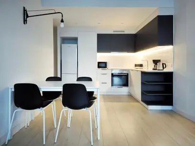 a kitchen with a table and black chairs at Apartamento céntrico, moderno, Terrassa Rambla in Terrassa