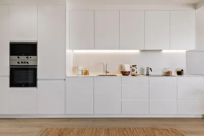 a white kitchen with white cabinets and appliances at Calella - 1 bedroom and terrace in Eixample Dreta in Barcelona