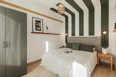 a kitchen with black cabinets and wooden chairs at Demir - 2 bedrooms and office in Vila de Gràcia in Barcelona