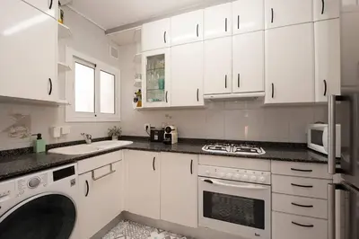 a kitchen with white cabinets and a washer and dryer at Beach vibes in Castelldefels in Castelldefels