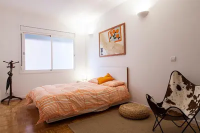 a bedroom with a bed and a chair and a window at Flateli Rossello 134 in Barcelona