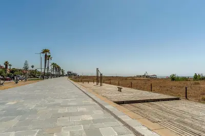 a walkway with palm trees on the side of a beach at Canela Homes COSTA PALMERES in Castelldefels