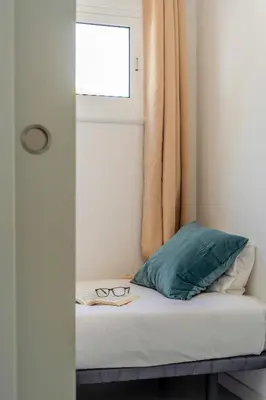 a bed with a window and a pair of glasses on it at Canela Homes COSTA PALMERES in Castelldefels