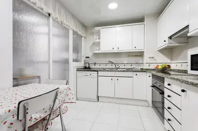 a kitchen with white cabinets and a table with a table cloth at Matarolux 2 in Mataró