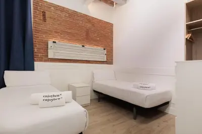 a room with two beds and a brick wall at Colon Deluxe con Piscina cerca del Mar in Barcelona