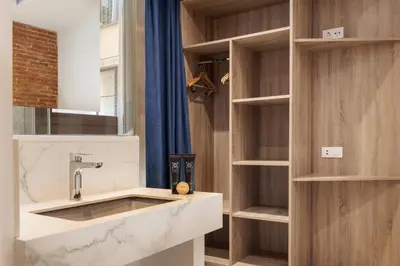 a bathroom with a sink and wooden shelves at Colon Deluxe con Piscina cerca del Mar in Barcelona