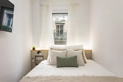 a bedroom with a bed with white pillows and a window at Barcelona Central Charm with Mediterranean Vibes in Barcelona
