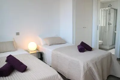 a bedroom with two beds with purple pillows on them at Cool & Modern Villa Giovanna with Air Conditioning, Private Pool & Sea Views in Sitges