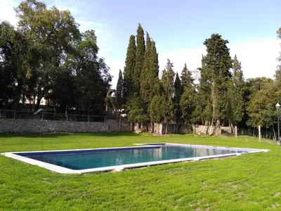 a swimming pool in the middle of a grass field at Hostal Rural Mas Blanc in San Martín de Centellas