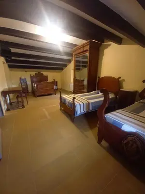 a large room with two beds and a piano at Hostal Rural Mas Blanc in San Martín de Centellas