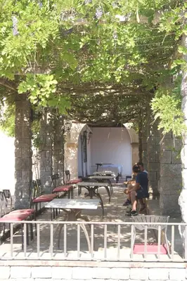 a group of tables and chairs under an arch with trees at Hostal Rural Mas Blanc in San Martín de Centellas